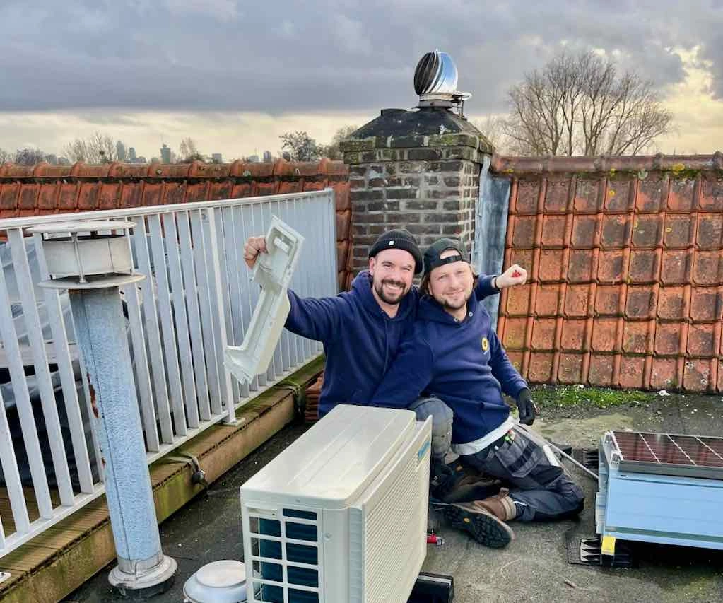 Tim en Daniel bij een buitenunit van Daikin op een dak